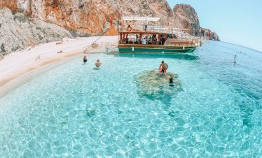 Tourists swimming at the western beach of Suluada, known for its white sand and turquoise water