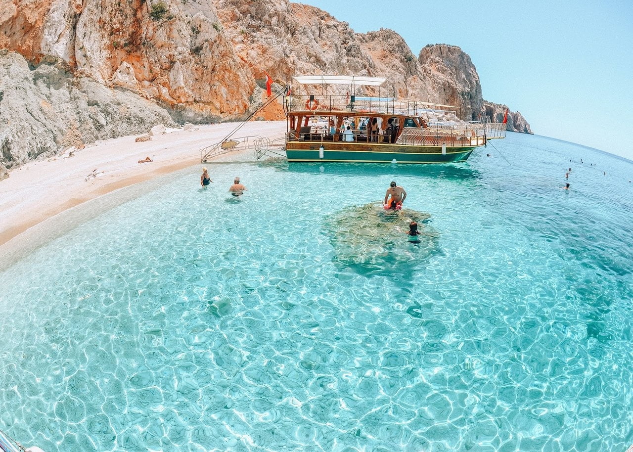 Tourists swimming at the western beach of Suluada, known for its white sand and turquoise water