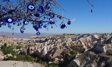 Nazar beads hanging at Lovers' Hill in Cappadocia with fairy chimneys in the background.