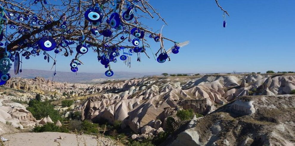Nazar beads hanging at Lovers' Hill in Cappadocia with fairy chimneys in the background.