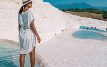 Woman in white dress standing in Pamukkale thermal pools with travertine terraces