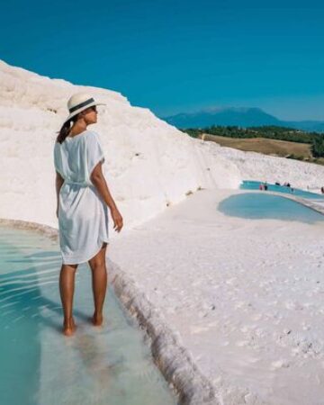 Woman in white dress standing in Pamukkale thermal pools with travertine terraces
