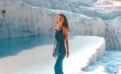 Smiling woman on Pamukkale travertine terraces, Turkey, with natural hot springs and ancient city views.