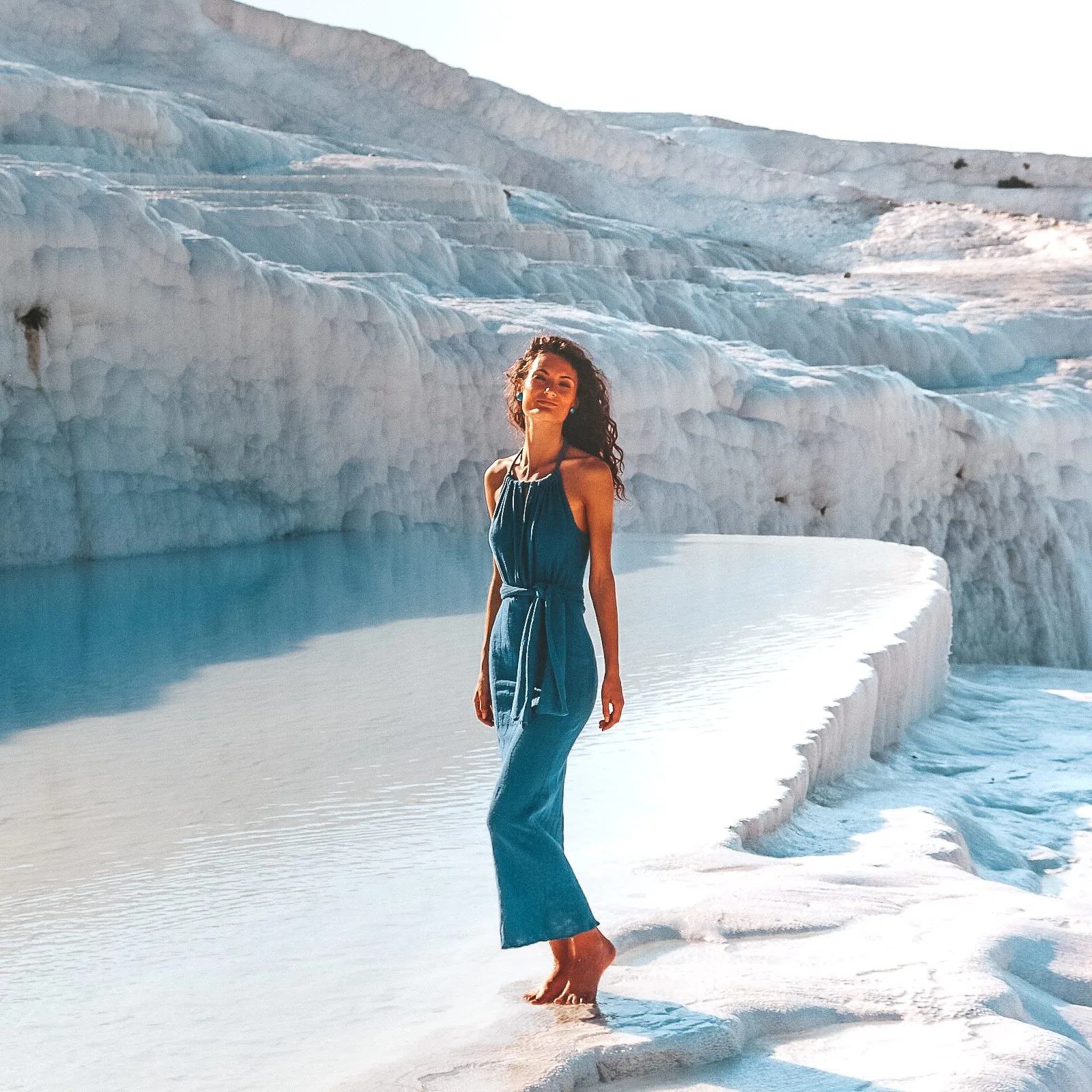 Smiling woman on Pamukkale travertine terraces, Turkey, with natural hot springs and ancient city views.